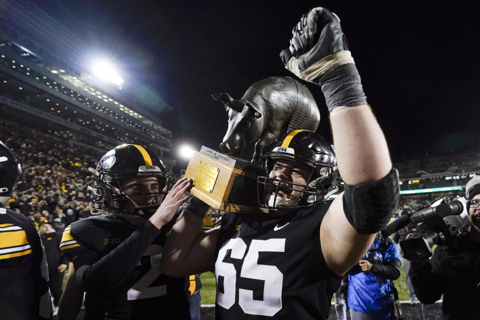 CORRECTS SCORE TO 27-22 INSTEAD OF 27-24 - Iowa offensive lineman Tyler Linderbaum (65) carries the Floyd of Rosedale trophy off the field after an NCAA college football game against Minnesota, Saturday, Nov. 13, 2021, in Iowa City, Iowa. Iowa won 27-22. (AP Photo/Charlie Neibergall)