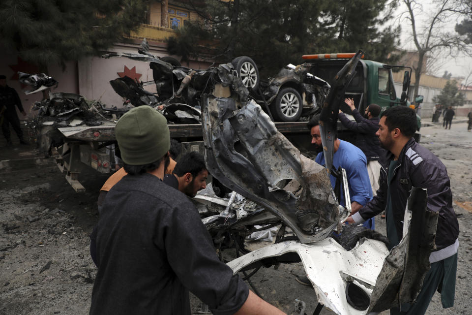 Afghan security personnel and people remove a damaged vehicle from the site of a bomb attack in Kabul, Afghanistan, Saturday, Feb. 20, 2021. Three separate explosions in the capital Kabul on Saturday killed and wounded numerous people an Afghan official said. (AP Photo/Rahmat Gul)