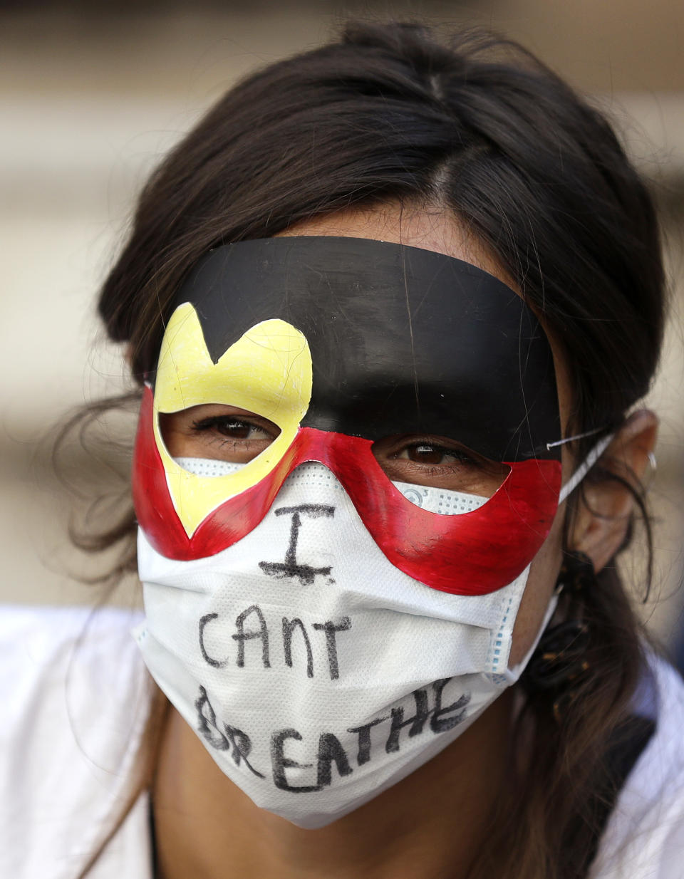 A protester wears a mask as thousands gather at Town Hall in Sydney, Saturday, June 6, 2020, to support the cause of U.S. protests over the death of George Floyd. Black Lives Matter protests across Australia proceeded mostly peacefully as thousands of demonstrators in state capitals honored the memory of Floyd and protested the deaths of indigenous Australians in custody. (AP Photo/Rick Rycroft)