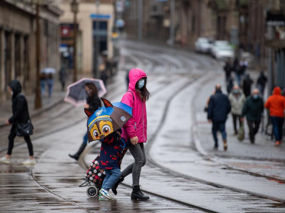 People hold umbrellas and don raincoats in the rain in Nottingham (PA)