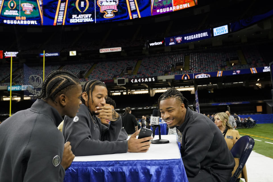 Texas defensive back Jahdae Barron, left, converses with teammates during media day for the the upcoming Sugar Bowl NCAA CFP college football semi-final game game in New Orleans, Saturday, Dec. 30, 2023. (AP Photo/Gerald Herbert)