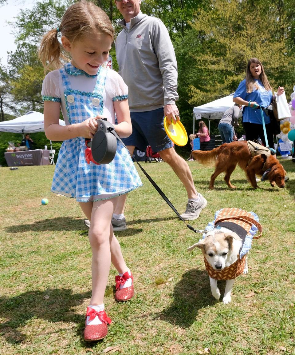 April 6, 2024; Tuscaloosa, Alabama, USA; Madison Leiter, dressed as Dorothy from the Wizard of Oz movie, walks with her dog, Jude during Bark in the Park at Sokol Park Saturday.