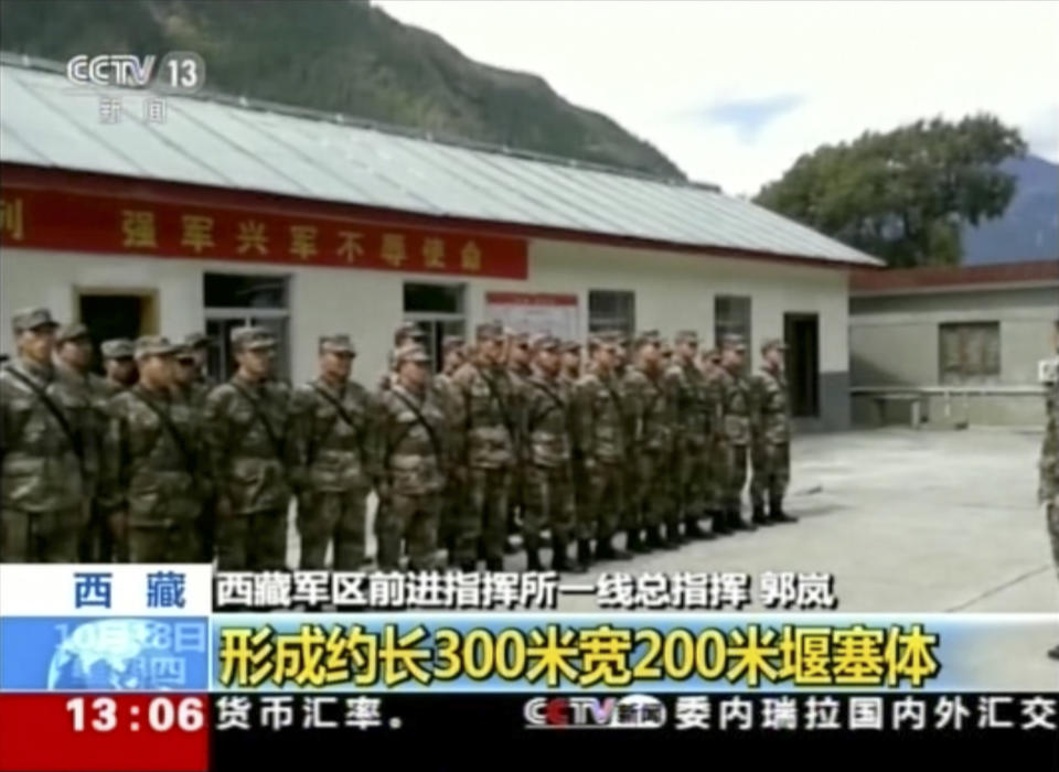 In this image from video footage run on Thursday, Oct. 18, 2018, by China's CCTV via AP Video, emergency response team prepare to deploy after a landslide formed a barrier lake on Yarlung Tsangpo in Tibet in western China. Thousands of people have been evacuated following a landslide in Tibet that blocked the flow of one of the region's key rivers, China's emergency services said Thursday. Yellow headline in Chinese reads: "Formed 300 meters by 200 meters barrier." (CCTV via AP Video)