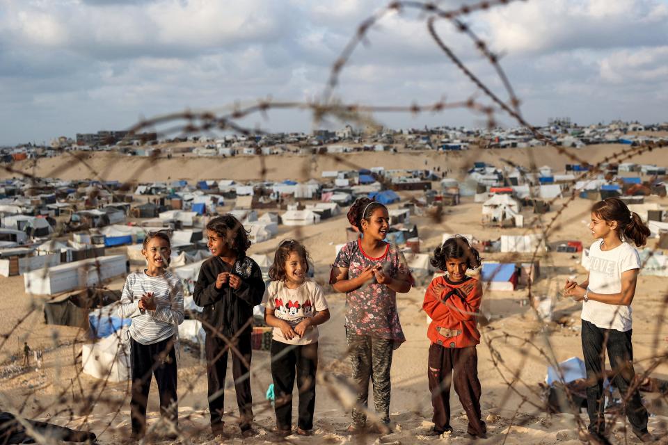 Children stand behind barbed wire near a camp housing displaced Palestinians in Rafah, in the southern Gaza Strip, on April 30, 2024.