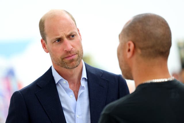 The Prince of Wales speaks to a man in a dark jumper