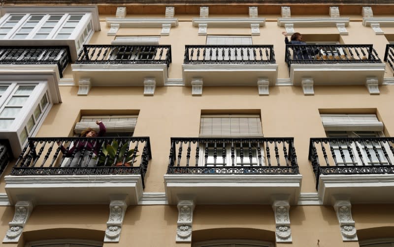 Women exercise on their balconies as they listen to the music in downtown Ronda