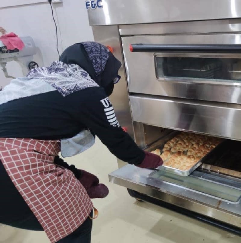 One of Ridzuan's workers taking out a tray of freshly made buns from the oven. ― Picture by Ridzuan Jamal