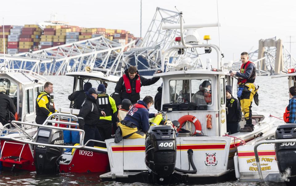 Rescue personnel gather on the shore of the Patapsco River