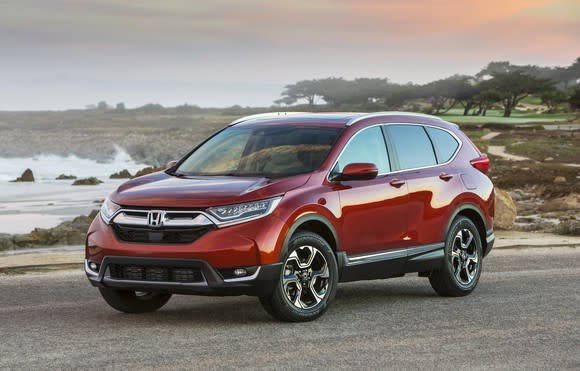 A red Honda CR-V, a compact crossover SUV, parked on a beach road.