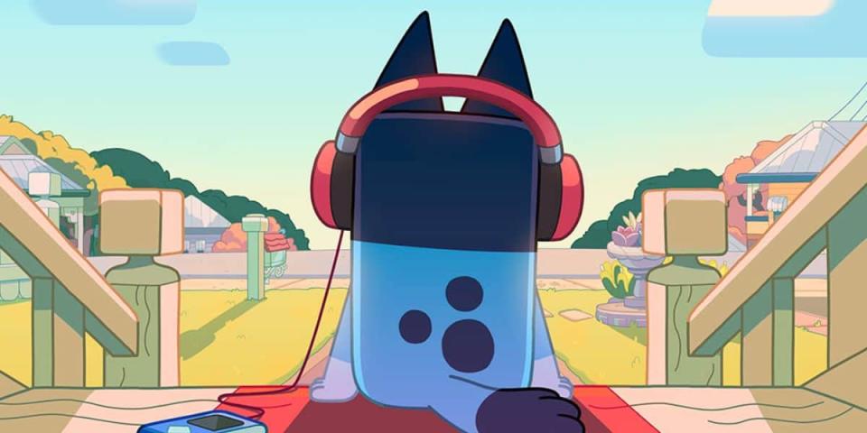 Bluey staring out at her front lawn while wearing headphones and listening to a music player. 