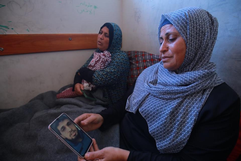 Umm Hassouna,  the mother of Hassouna Saliem,  and his aunt Afaf Abu Sukran,  hold a photo of the slain journalist.