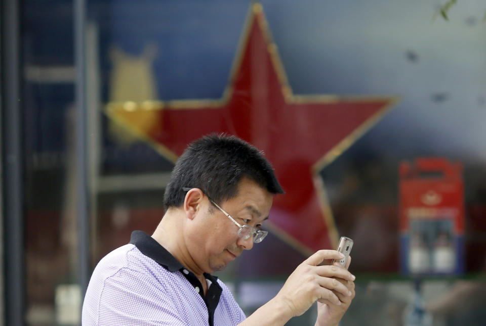 <p>A man uses his mobile phone near a red star along a retail shop in Beijing May 20, 2016. China’s government fabricates and posts several hundred million social media posts a year to influence public opinion about the country, according to a new paper by U.S. researchers examining one of the most opaque aspects of the Communist Party’s rule. (Ng Han Guan/AP) </p>