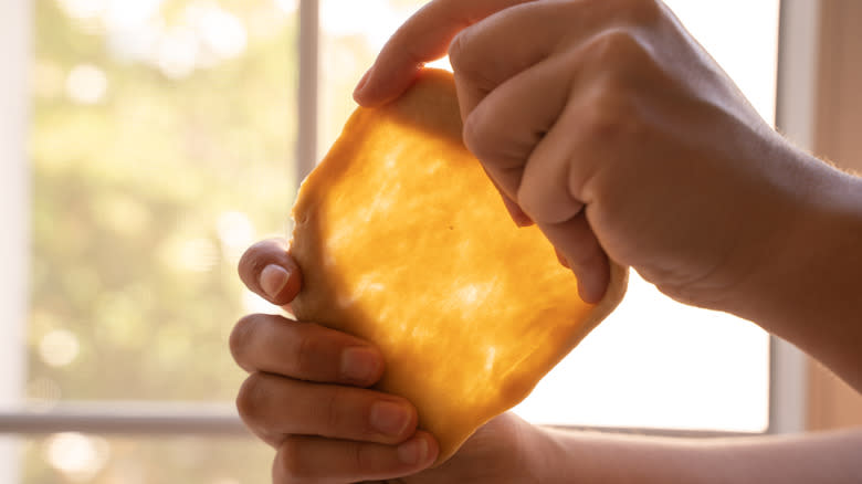 Person pulling a window in dough in front of a kitchen window