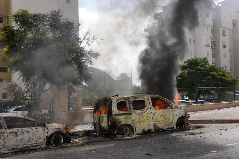 FILE - Cars are on fire after they were hit by rockets from the Gaza Strip in Ashkelon, Israel, Oct. 7, 2023. Israel expects its top ally, the United States, to announce that it’s blocking military aid to an Israeli army unit over gross human rights abuses in the Israeli-occupied West Bank before the war in Gaza began six months ago. The move would mark the first time that a U.S. administration has invoked a 27-year-old congressional act known as the Leahy law against an Israeli military unit.(AP Photo/Ohad Zwigenberg, File)