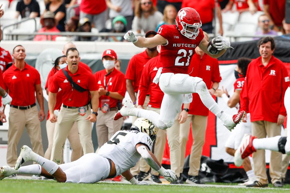 Rutgers Scarlet Knights quarterback Johnny Langan (21) leaps over Wake Forest Demon Deacons linebacker Ryan Smenda Jr. (5) for extra yards in the second quarter at TIAA Bank Field at the TaxSlayer Gator Bowl in Jacksonville on Dec. 31, 2021. Mandatory Credit: Nathan Ray Seebeck-USA TODAY Sports