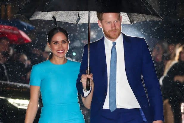 Meghan Markle and Prince Harry walk underneath an umbrella on a rainy night in London in 2020.