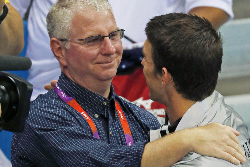 FILE - Coach Bob Bowman hugs United States' Michael Phelps after Phelps was honored as the most decorated Olympian at the Aquatics Centre in the Olympic Park during the 2012 Summer Olympics in London, Aug. 4, 2012. Bowman has been like a father to Phelps, who is married with three young sons — youngsters that the coach views as his grandchildren. (AP Photo/Julio Cortez, File)