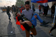 An injured protester is rushed to a hospital during clashes with security forces on the closed Joumhouriya Bridge that leads to the Green Zone government areas, in Baghdad, Iraq, Sunday, Oct. 25, 2020. Thousands of Iraqi protesters have taken to the streets to mark one year since mass anti-government demonstrations swept Baghdad and Iraq's south. Protesters marched Sunday in the capital and several southern cities to renew demands to bring an end to corruption perpetuated by Iraq's politicians. (AP Photo/Khalid Mohammed)