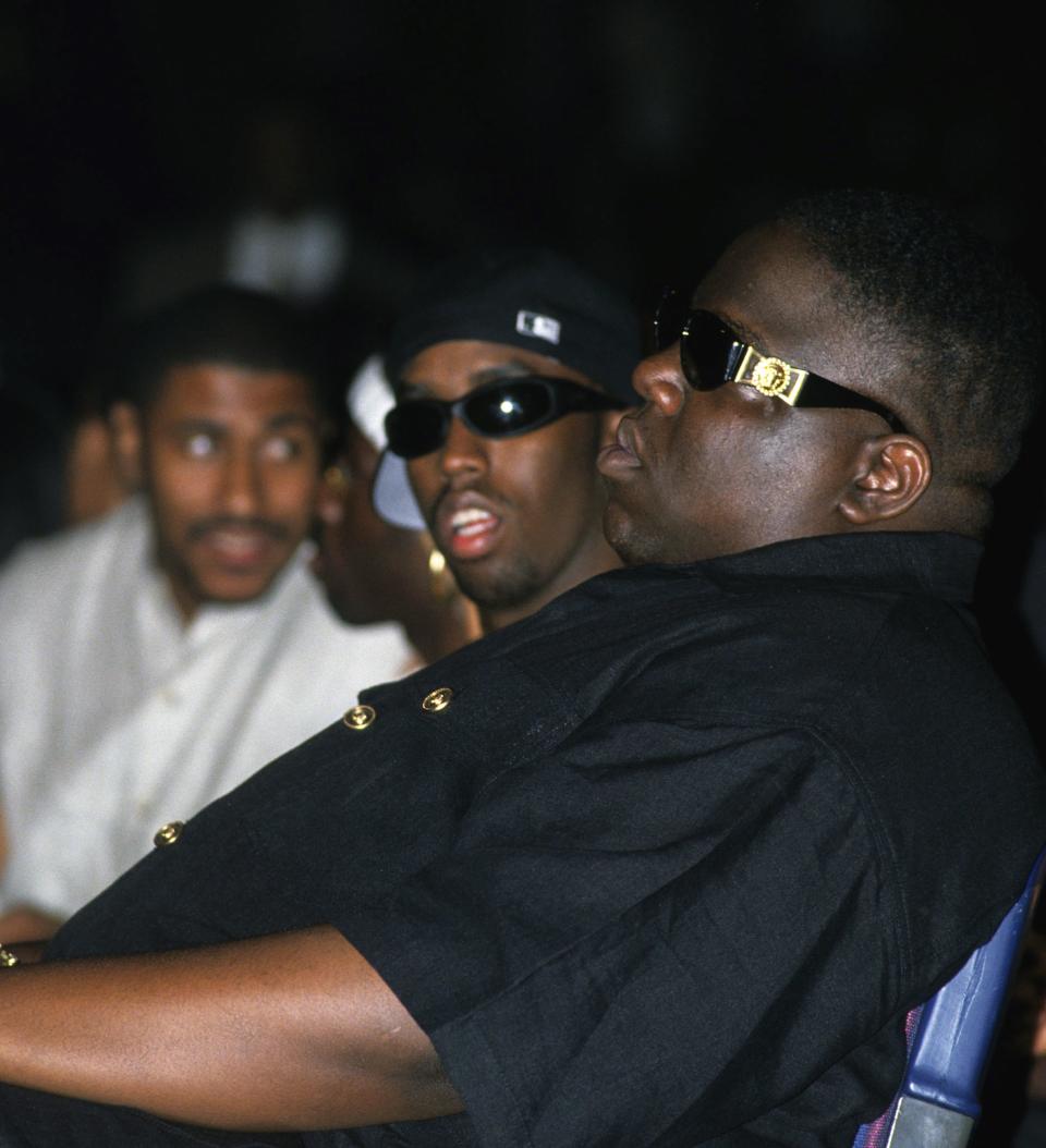 NEW YORK – AUGUST 3: Rappers <a href="https://www.vibe.com/t/the-notorious-b-i-g/" rel="nofollow noopener" target="_blank" data-ylk="slk:The Notorious B.I.G.;elm:context_link;itc:0;sec:content-canvas" class="link ">The Notorious B.I.G.</a> aka Biggie Smalls (Christoper Wallace) and Puff Daddy (Sean Combs) take in Dr. Dre’s performance at the second Source Awards at the Palladium on August 3, 1995 in New York, New York (Photo by Al Pereira/Michael Ochs Archives/Getty Images)