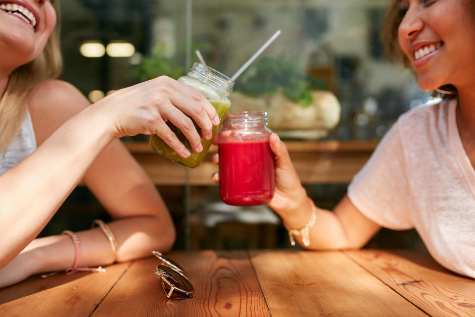 Close up shot of female friends toasting juice glasses at sidewalk cafe. (PHOTO: Getty Images)