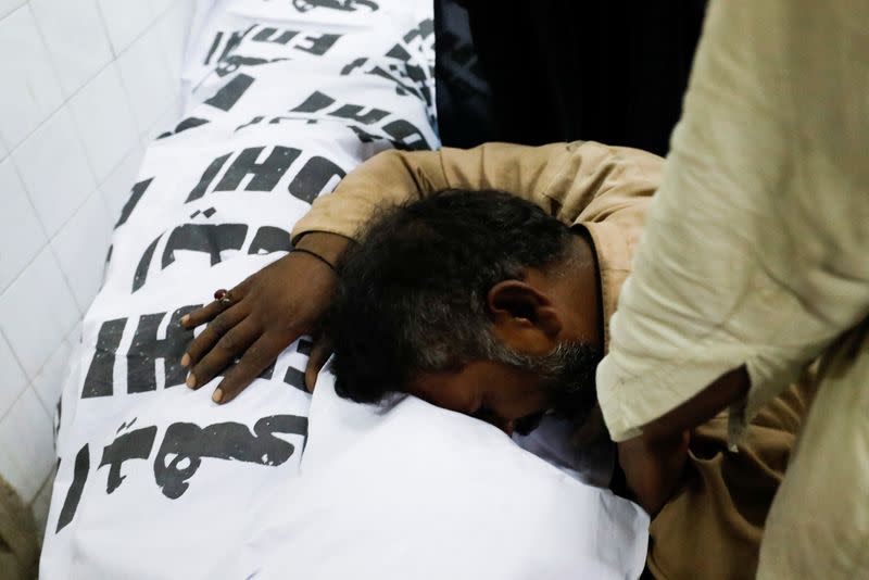 People mourn the death of a relative, who was killed along with others in a stampede during handout distribution, in Karachi