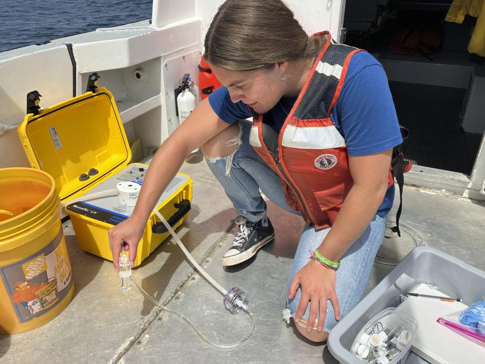 In this photo provided by Thunder Bay National Marine Sanctuary, Michigan Sea Grant intern Cassidy Beach collects Lake Huron water samples aboard a research vessel on July 13, 2022, near Alpena, Mich. Beach was assisting a multi-year project at Thunder Bay Marine Sanctuary to determine whether the lake is becoming more acidic. (Thunder Bay National Marine Sanctuary/NOAA via AP)