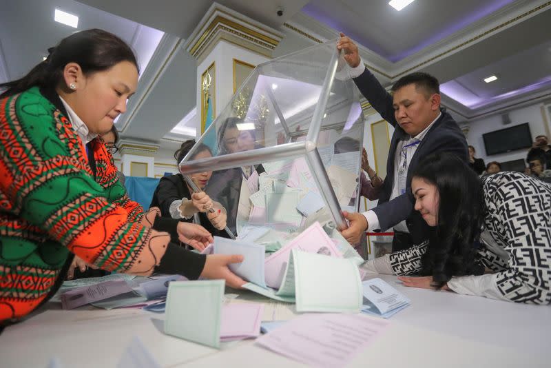 Members of a local election committee empty a ballot box to count votes after polls closed during parliamentary election in Almaty