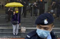 A pro-democracy supporter holding an umbrella queues up for a hearing outside a courthouse in Hong Kong, Thursday, March 4, 2021. A marathon court hearing for 47 pro-democracy activists in Hong Kong charged with conspiracy to commit subversion enters its fourth day on Thursday, as the court deliberates over whether the defendants will be granted bail. (AP Photo/Vincent Yu)