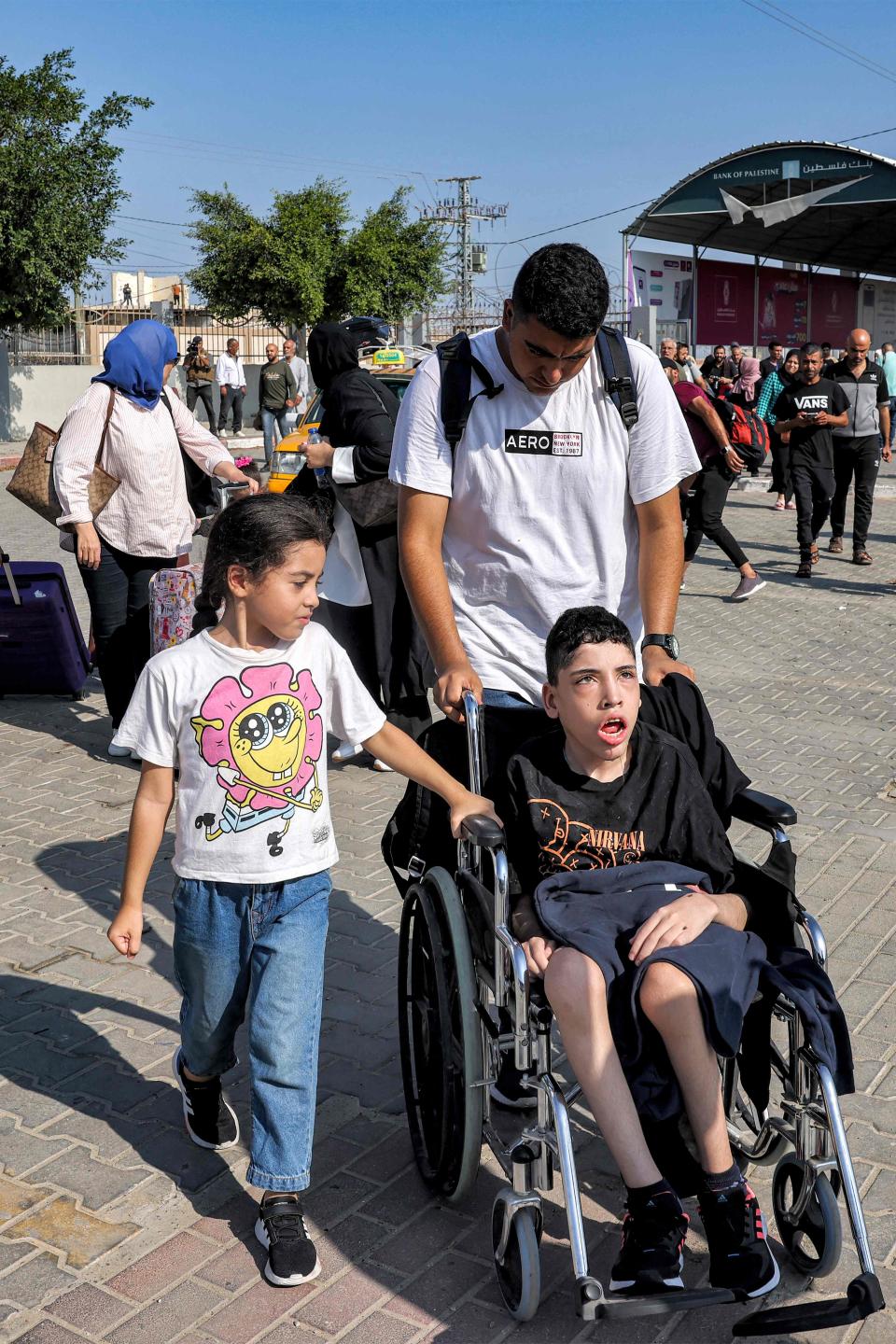 A man pushes a child on a wheelchair as people enter the Rafah border crossing (AFP via Getty Images)