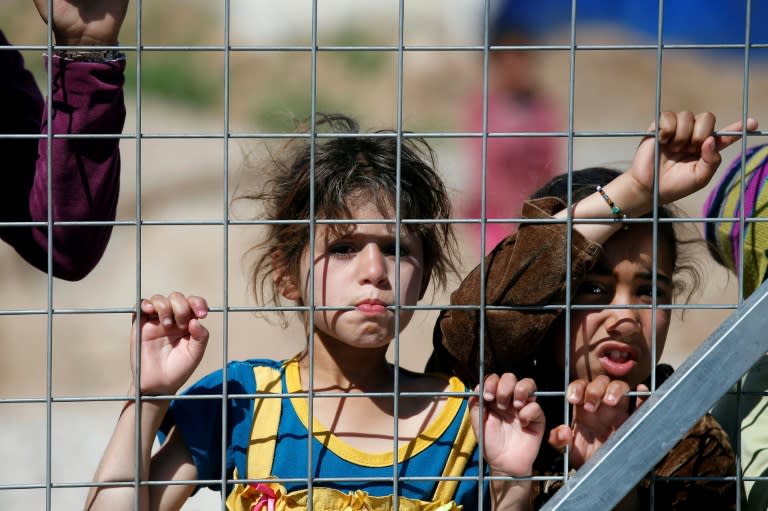 Iraqi children displaced from the battleground city of Mosul stand behind a fence at a camp in the village of Hasan Sham, 30 kilometres (18 miles) away