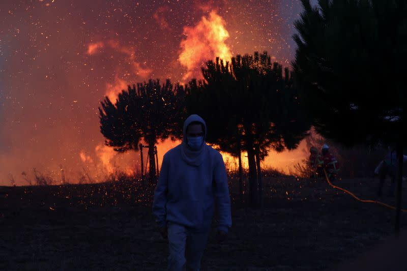 A person walks near a wildfire in Cascais