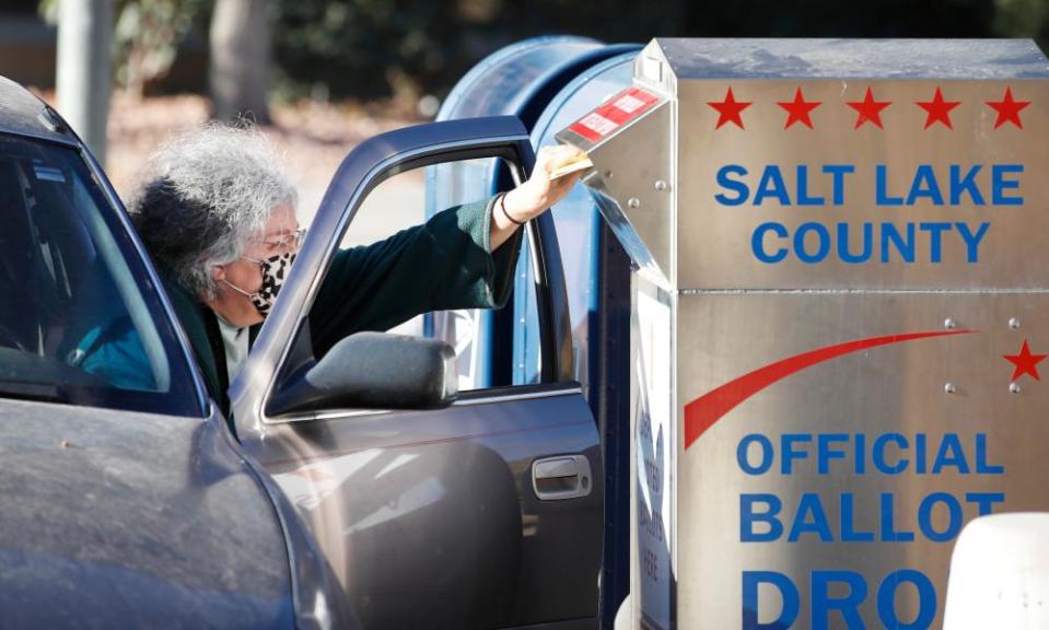 A voter drops off her mail in ballot at a drop box at the Salt Lake County election office in Utah.