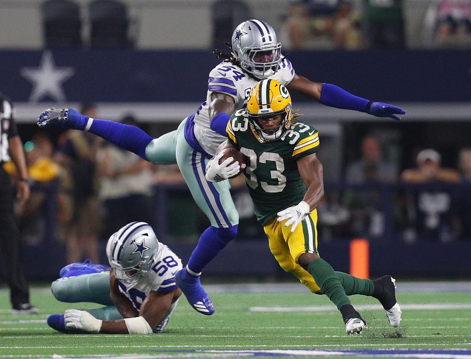 Aaron Jones #33 of the Green Bay Packers evades Jaylon Smith #54 and Robert Quinn #58 of the Dallas Cowboys in the fourth quarter at AT&T Stadium on October 06, 2019 in Arlington, Texas.