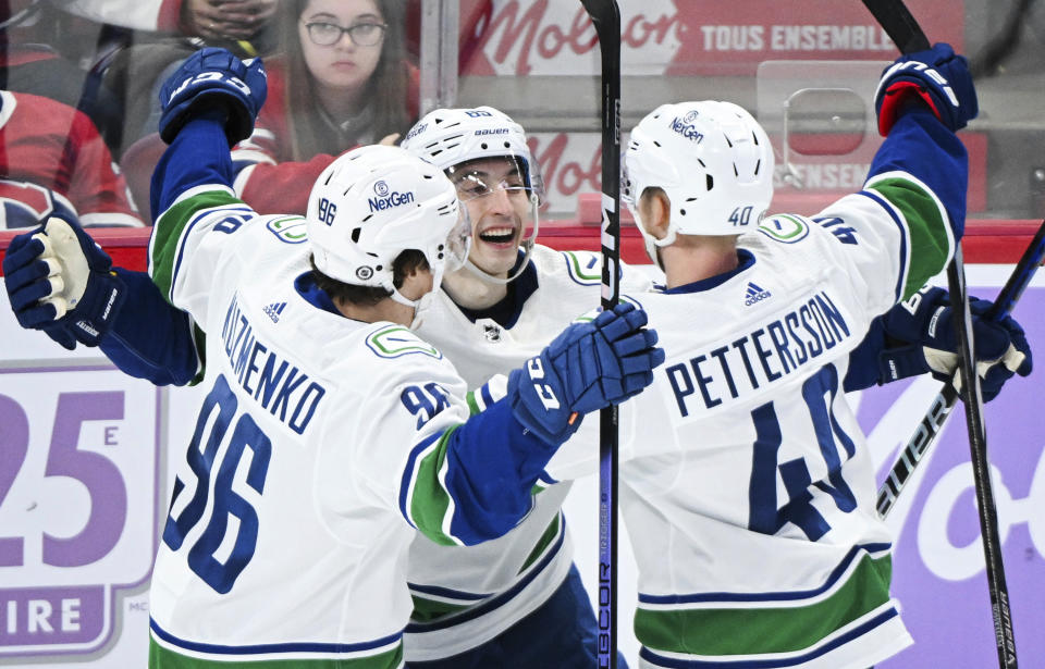 Vancouver Canucks' Ilya Mikheyev (65) celebrates with teammates Andrei Kuzmenko (96) and Elias Pettersson (40) after scoring against the Montreal Canadiens during second-period NHL hockey game action in Montreal, Sunday, Nov. 12, 2023. (Graham Hughes/The Canadian Press via AP)