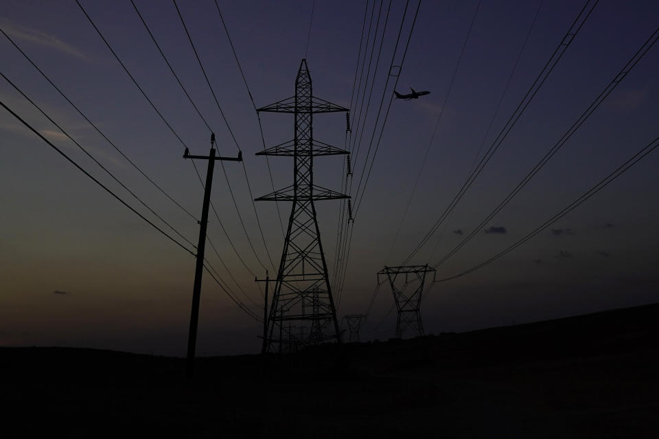 An airplane passes power lines as the sun sets, Sunday, Aug. 20, 2023, in San Antonio. Triple digit temperatures continue to stress the power grid. (AP Photo/Eric Gay)