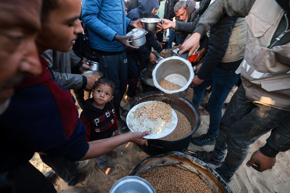 Displaced Palestinians collect food donated by a charity before an iftar meal, the breaking of fast, on the first day of the Muslim holy fasting month of Ramadan, in Rafah in the southern Gaza Strip on March 11, 2024, amid ongoing battles between Israel and the militant group Hamas.