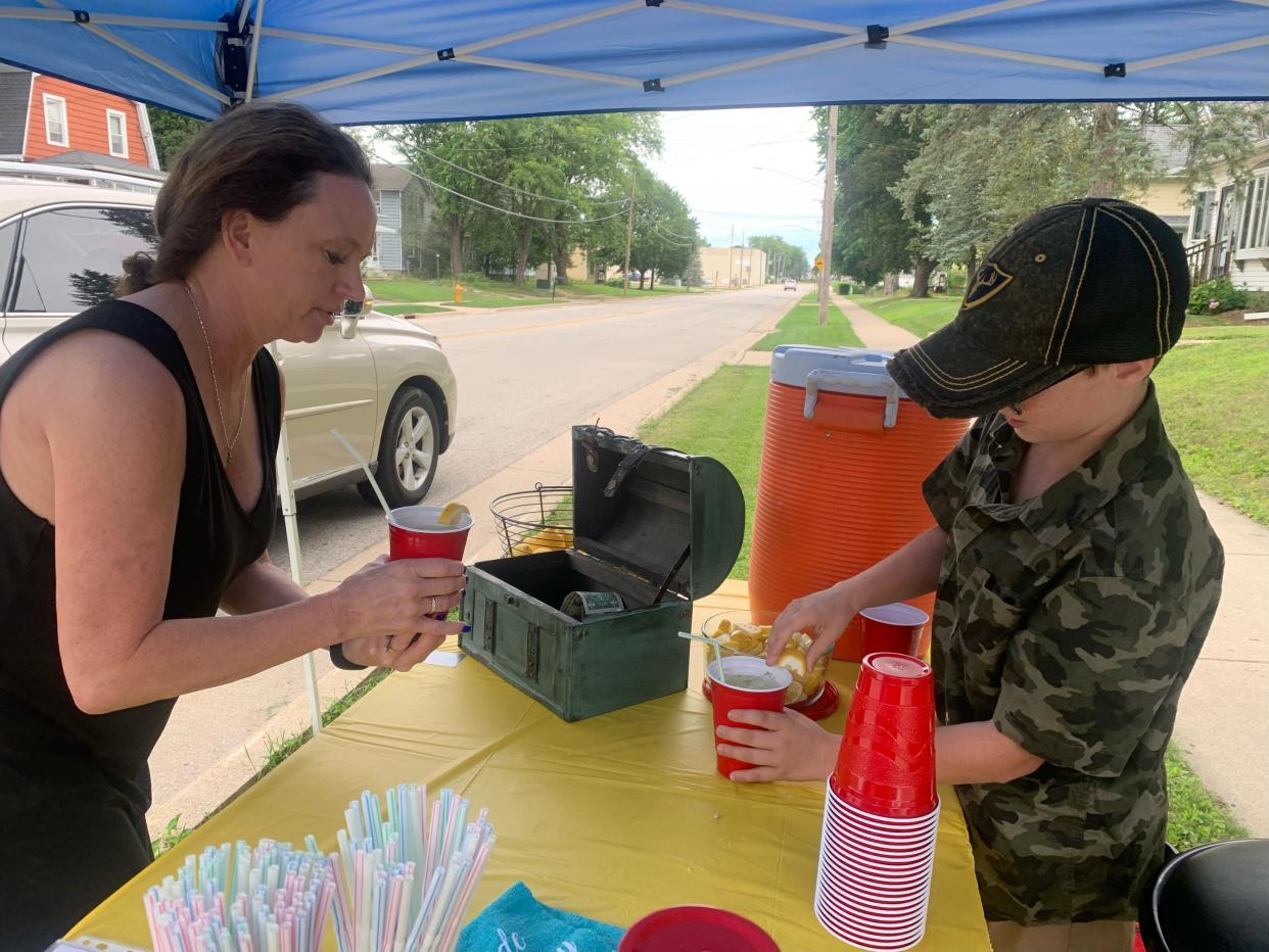 Camden Hoeft, 10, prepares a lemonade for Trina Conigliaro on Aug. 12 at his Oconommowoc stand. Camden is using the lemonade stand to fundraise for Children's Wisconsin.