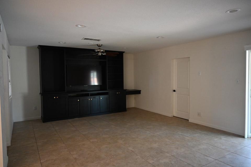 An empty living room aside from a black built-in shelf.