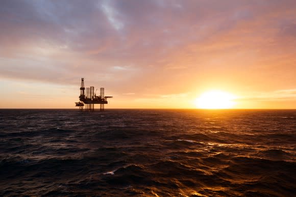 A silhouette of an offshore drilling rig at sunset.