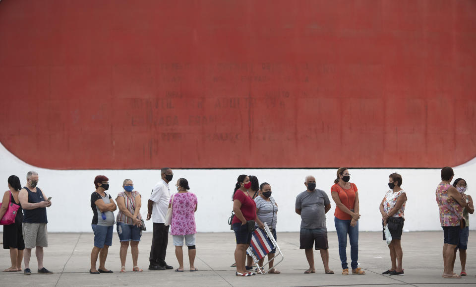 People wait in line to get the Sinovac vaccine at a COVID-19 vaccination point for seniors in Duque de Caxias, Brazil, Wednesday, March 24, 2021. (AP Photo/Silvia Izquierdo)