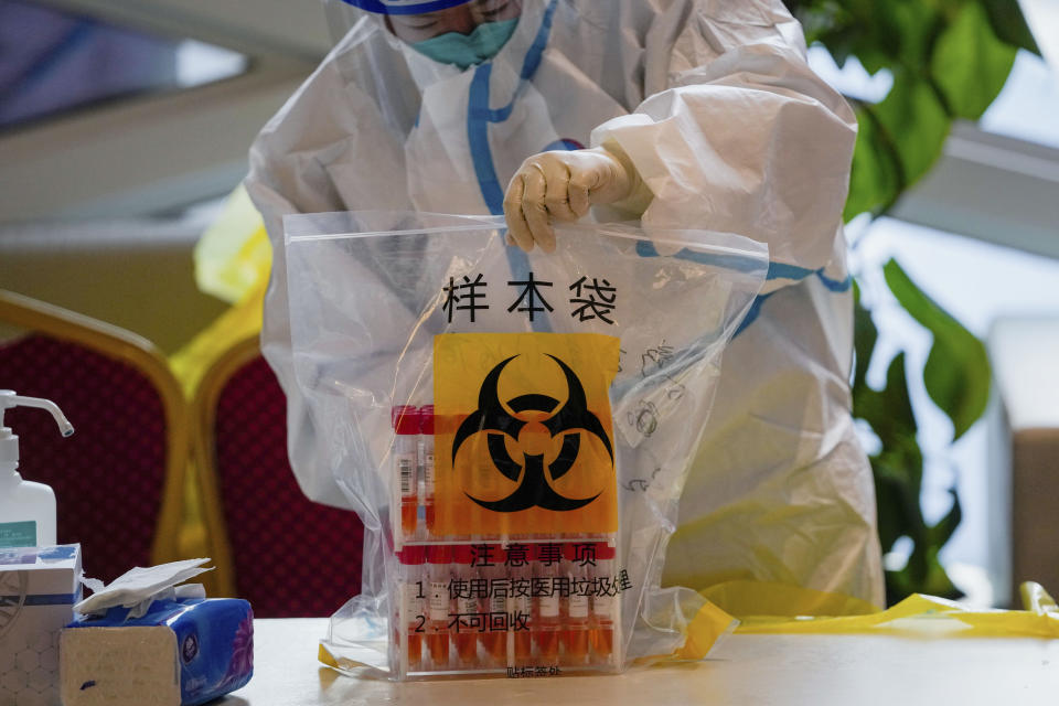 A health worker wearing a protective suit seals off a bag containing the COVID-19 test samples at a hotel used for people to stay during a period of health quarantine Sunday, March 20, 2022, in the Yanqing district of Beijing. (AP Photo/Andy Wong)