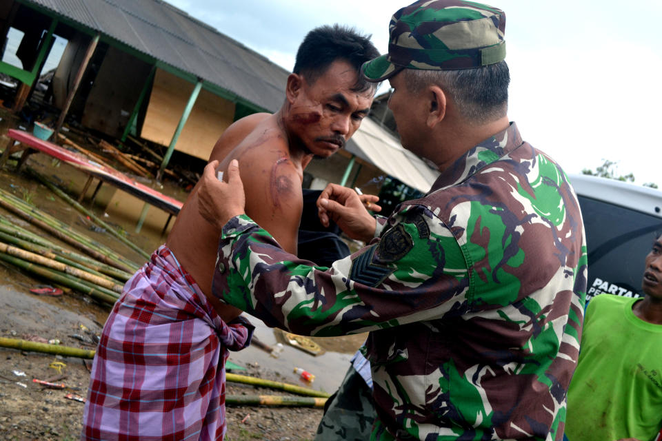 A soldier examines as he takes care of a local resident who was injured following a tsunami which hit at Tanjung Lesung district in Pandeglang, Banten province, Indonesia, Dec. 23, 2018. (Photo: Antara Foto/Muhammad Bagus Khoirunas via Reuters)