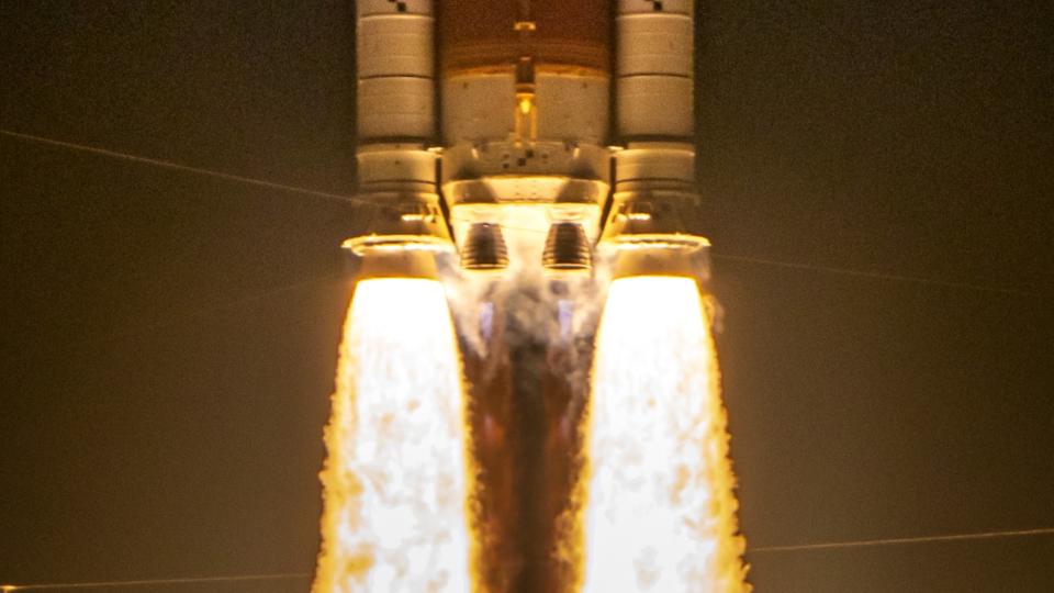  Two massive side booster spew yellow orange fire lifting the core stage of a rocket as two main engines also ignite . 