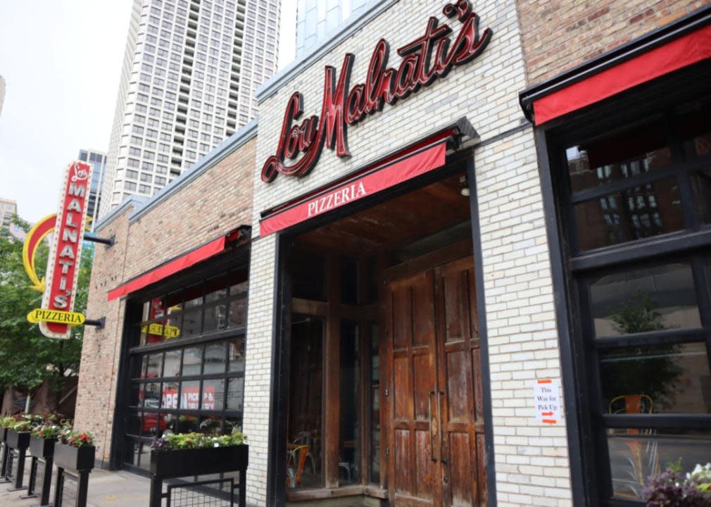 A brick Lou Malnati's restaurant with a red sign and tall wood door.