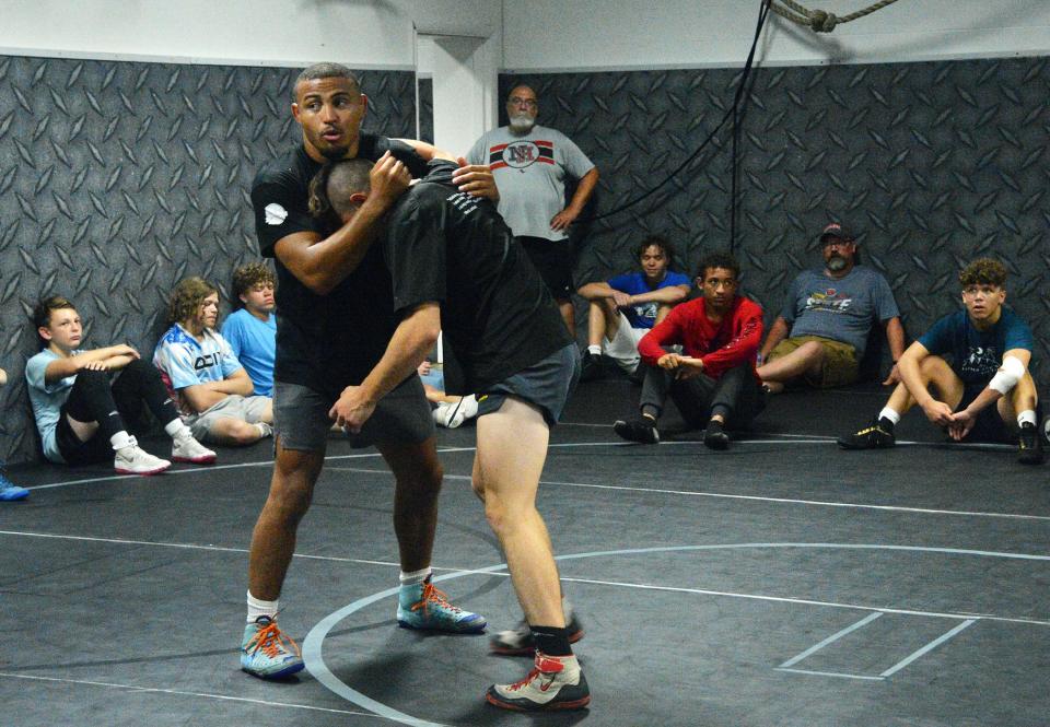 Aaron Brooks demonstrates an underhook technique with Thomas Monn as campers and North Hagerstown coach Greg Slick look on during the PAL wrestling camp Saturday at Fairgrounds Park.