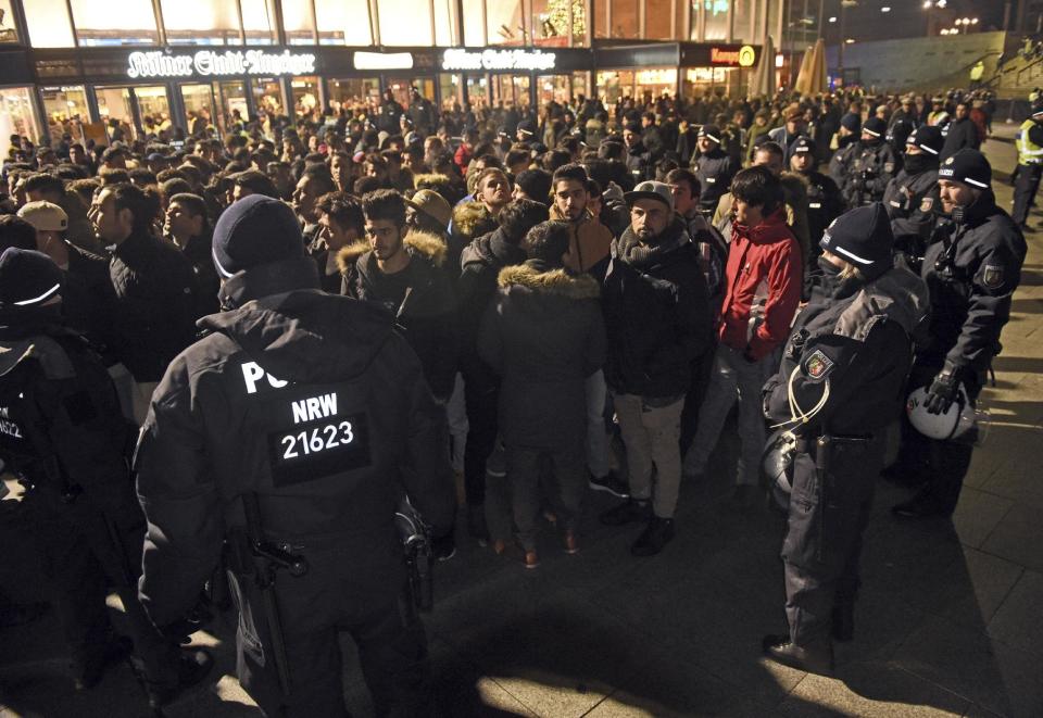 Police officers surround a group of men in front of the Cologne, western Germany, main station, Saturday, Dec. 31, 2016, where a string of robberies and sexual assaults last year that were blamed largely on migrants from North Africa prompted nationwide outrage. (Henning Kaiser/dpa via AP)