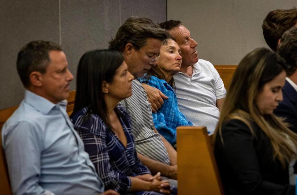 Right to left, Carlos Naibryf hugs his wife, Ronit Felszer, as Neil Handler, center, and Andrea and Pablo Langesfeld listen to lawyers during court proceedings Thursday in Miami. They and other family members were in the court as the deal to resolve class-action litigation was discussed.