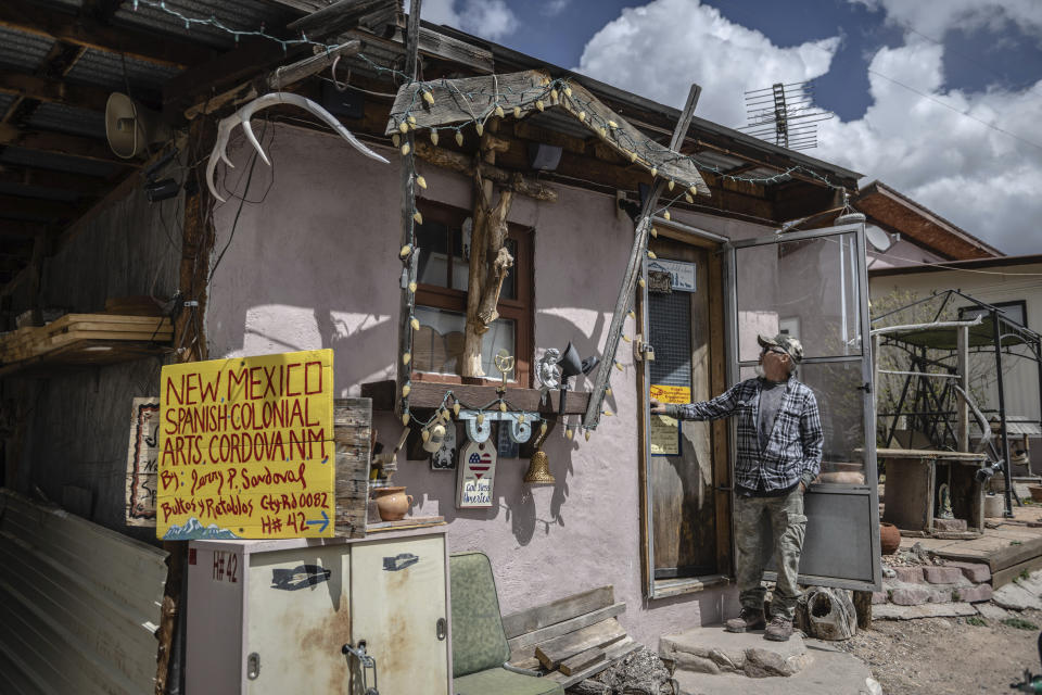 Santero Jerry Sandoval stands outside his studio in Cordova, New Mexico, Friday, April 14, 2023. Sandoval paints his bultos, or wooden saints, with natural pigments – purple is made of crushed cochineal beetles, for example – and varnishes them with the sap of pinon, the stocky pine tree that dots the countryside. (AP Photo/Roberto E. Rosales)