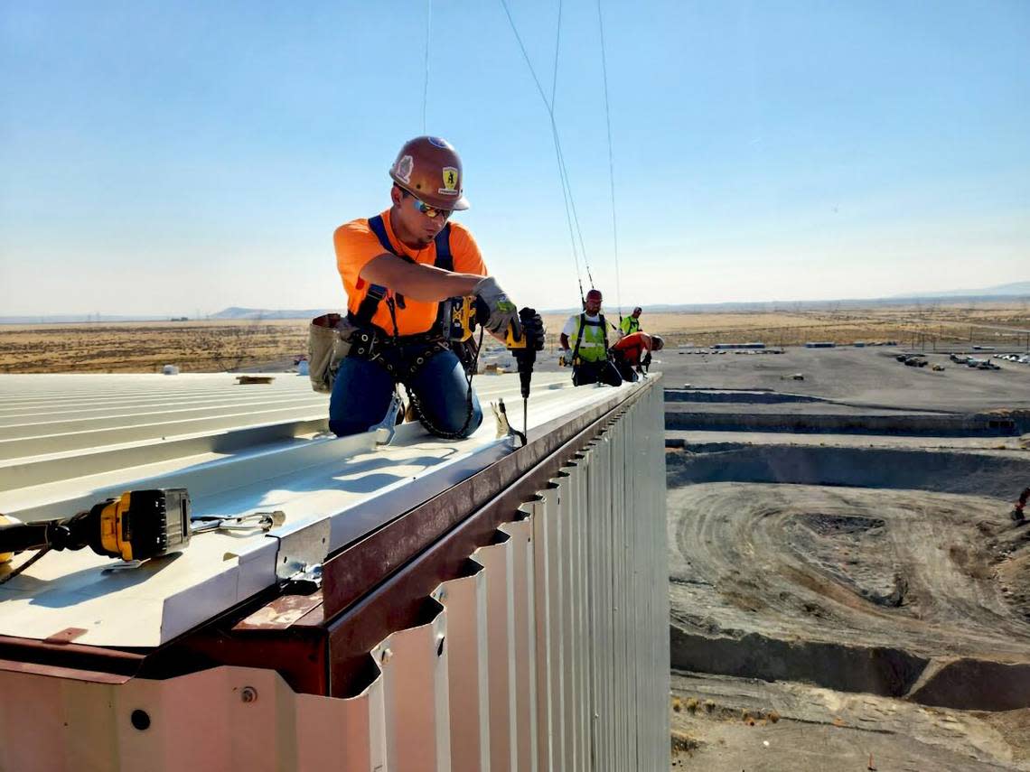 A worker makes progress on installing the roof of the cocoon over the Hanford K East Reactor. The cocoon stands about 120 feet tall.