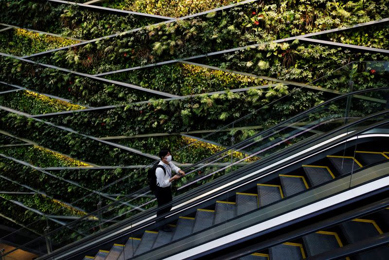 A man wearing a protective mask rides an escalator at a business building as the nation's capital, Tokyo, reported 31,878 cases of daily infections, surpassing the 30,000 mark for the first time amid the coronavirus disease (COVID-19) pandemic in Tokyo
